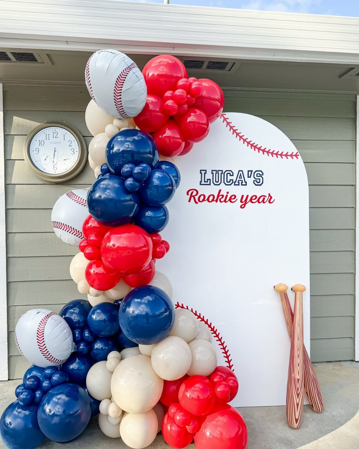 Baseball party backdrop with red, white, and blue balloons and wooden bats.