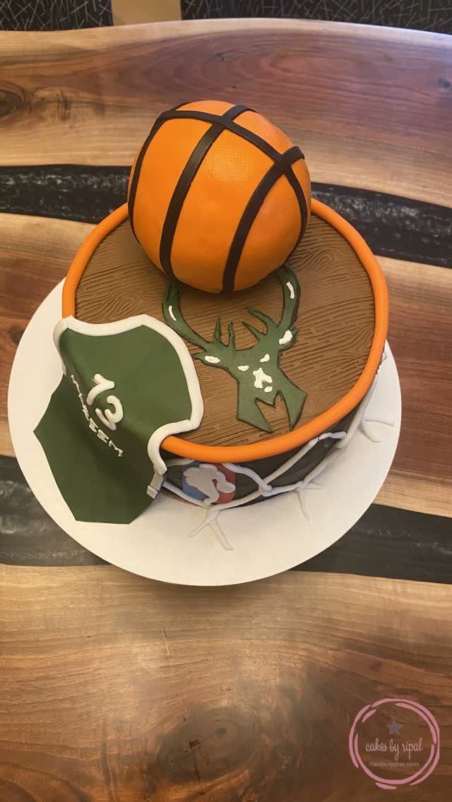 Basketball court cake with a spherical basketball topper and a green jersey decoration.