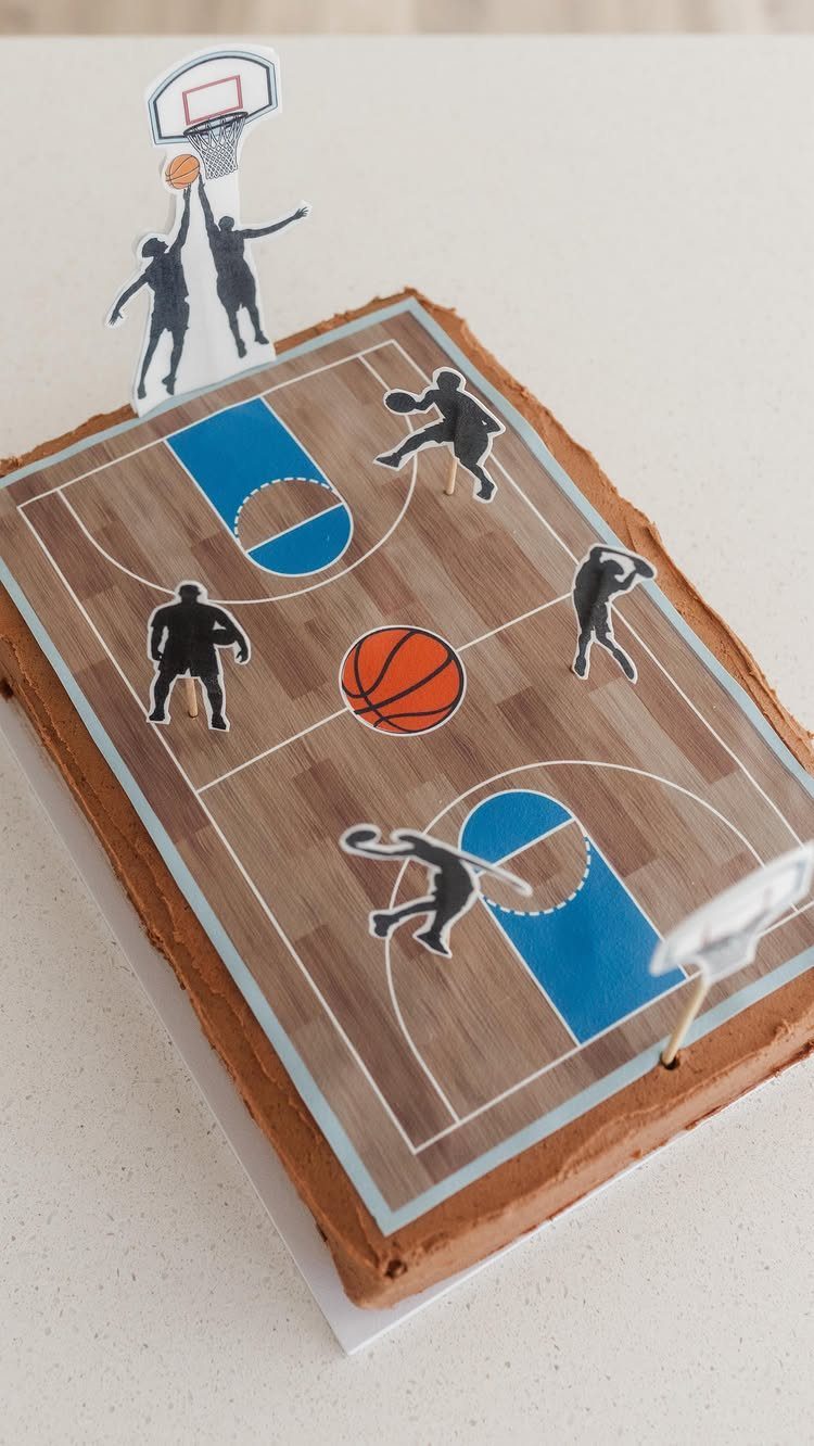 Rectangular chocolate cake topped with an edible basketball court print and player toppers.