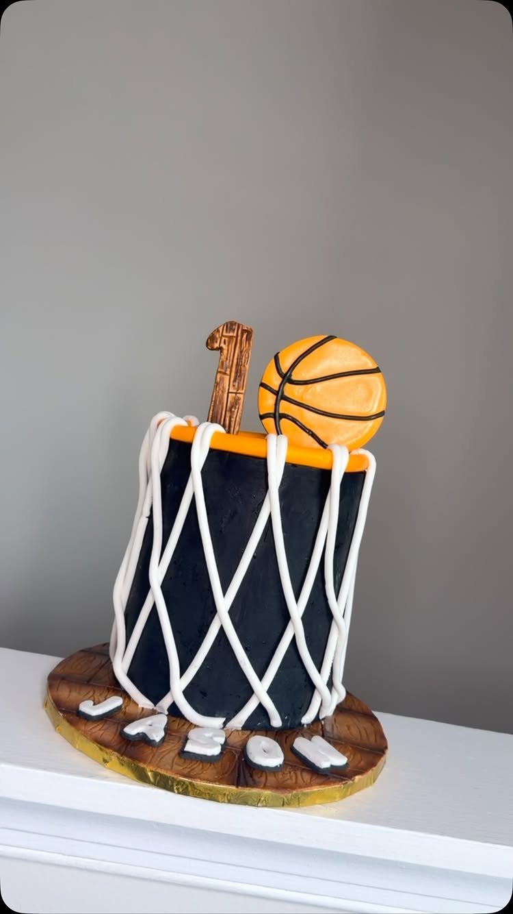 Basketball hoop cake with white netting, orange rim, and a small basketball topper.