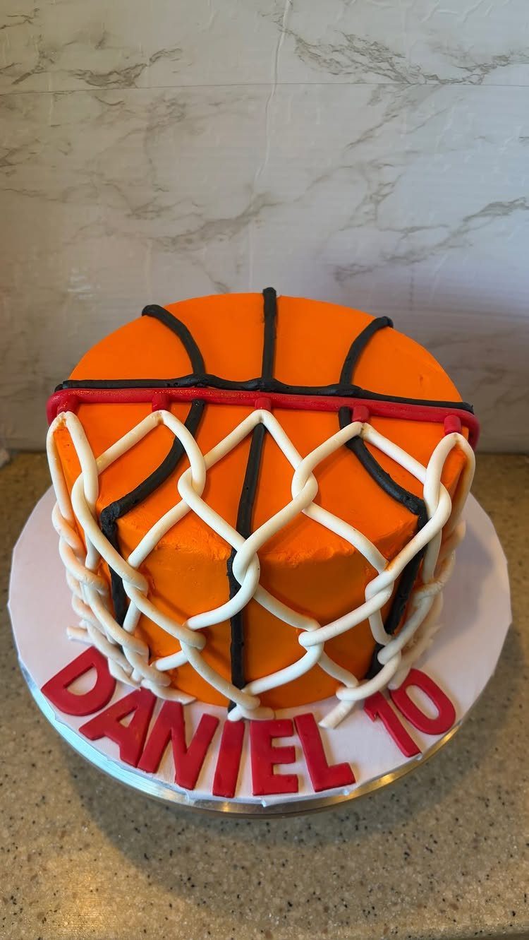 Basketball cake wrapped in a white frosting net with red name lettering below.