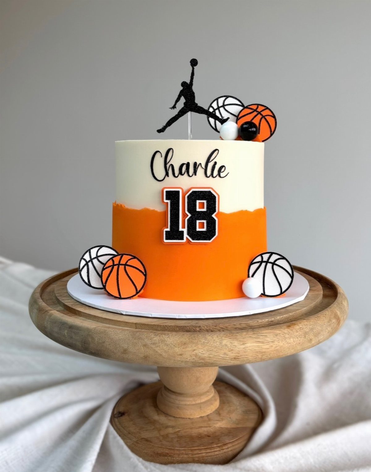Basketball birthday cake with orange and white frosting, number 18, and player silhouette.
