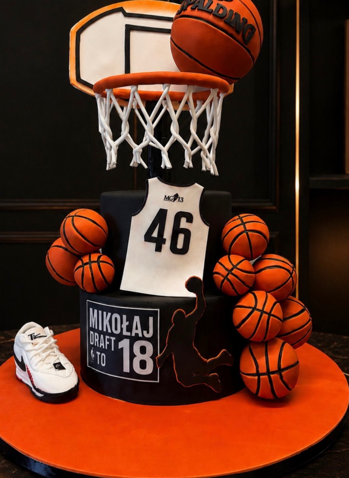 Basketball themed birthday cake with a hoop, jersey, and orange basketball decorations.