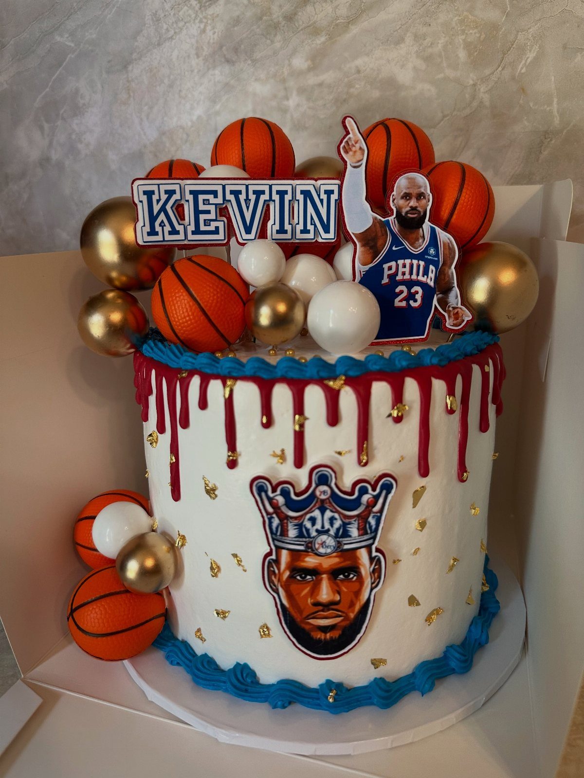 White basketball cake with red drip, orange basketball decorations, and LeBron James images.