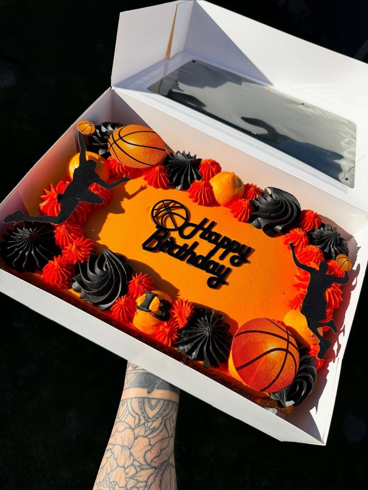 Orange basketball sheet cake with black frosting, basketball toppers, and Happy Birthday sign.