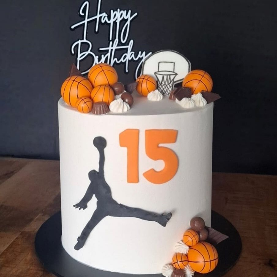 White basketball birthday cake with a hoop topper, orange basketballs, and number 15.