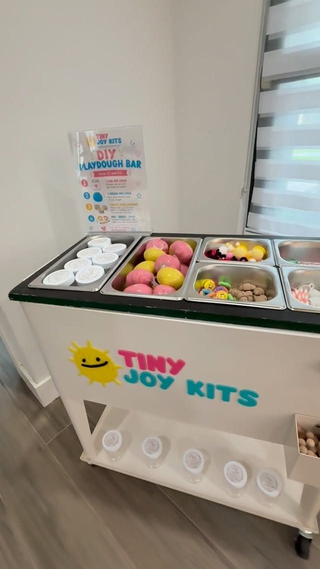 DIY playdough bar on a white cart with colorful dough and toys