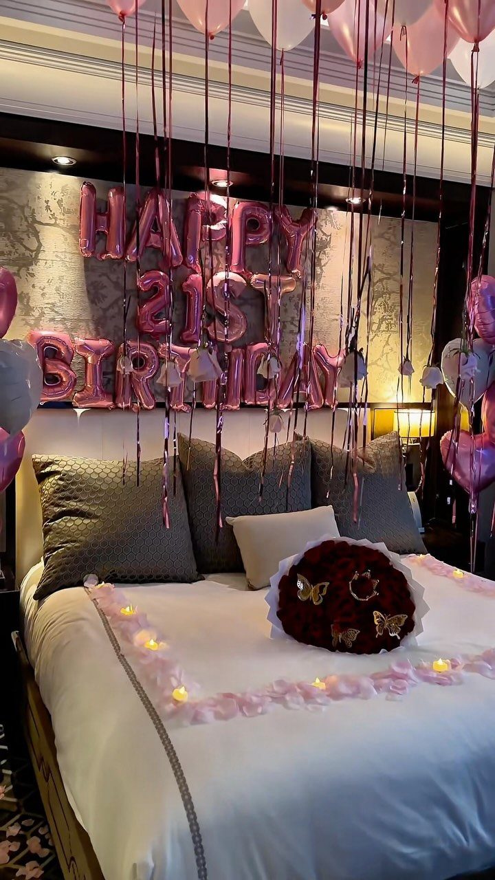 Bed decorated with pink balloons, 21st birthday foil letters, and red rose heart.