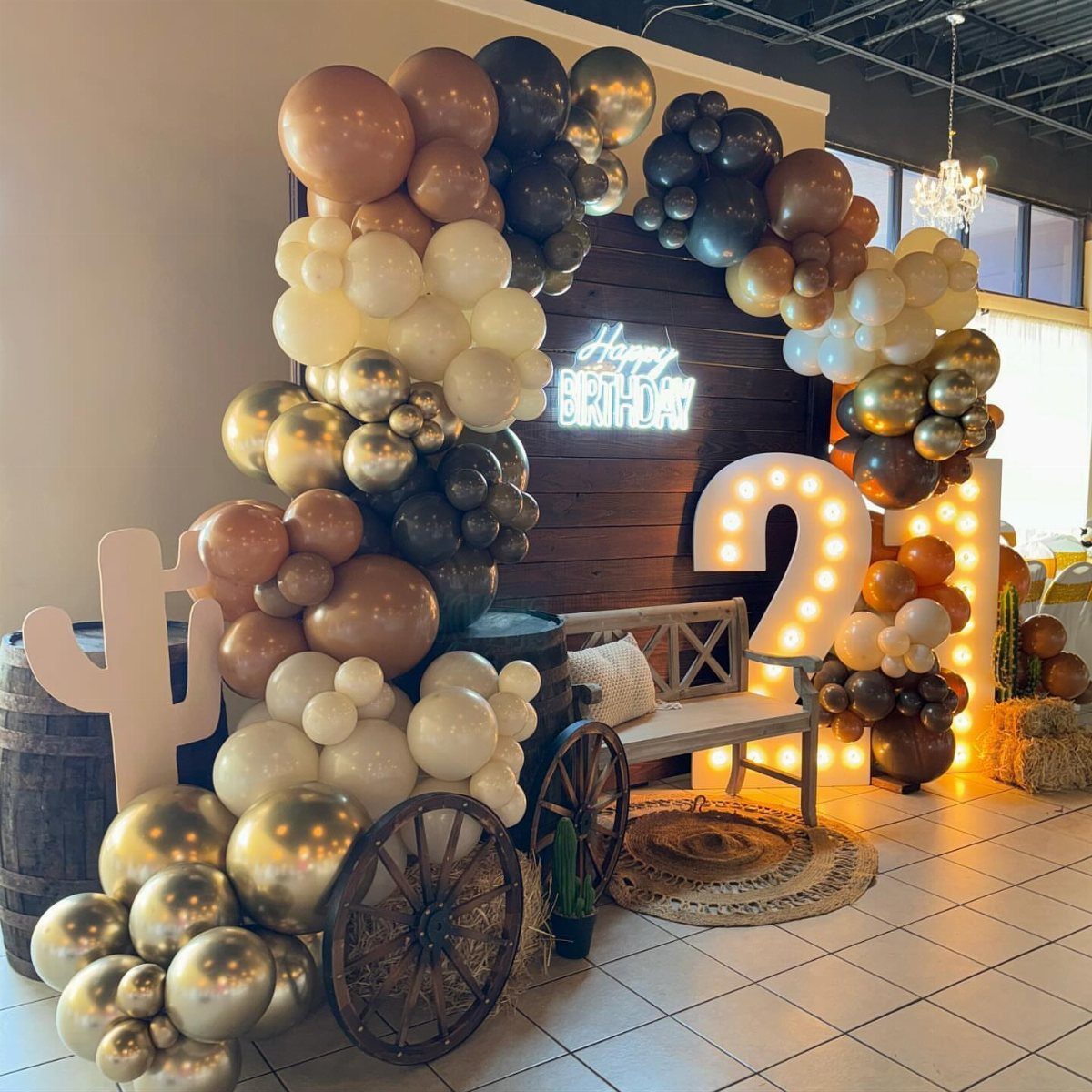 Birthday party setup with gold balloons, glowing 21 sign, and rustic western decor.