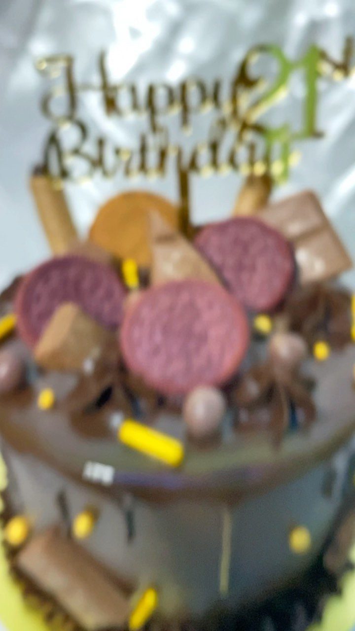Chocolate birthday cake with candies and a gold Happy 21st Birthday topper.