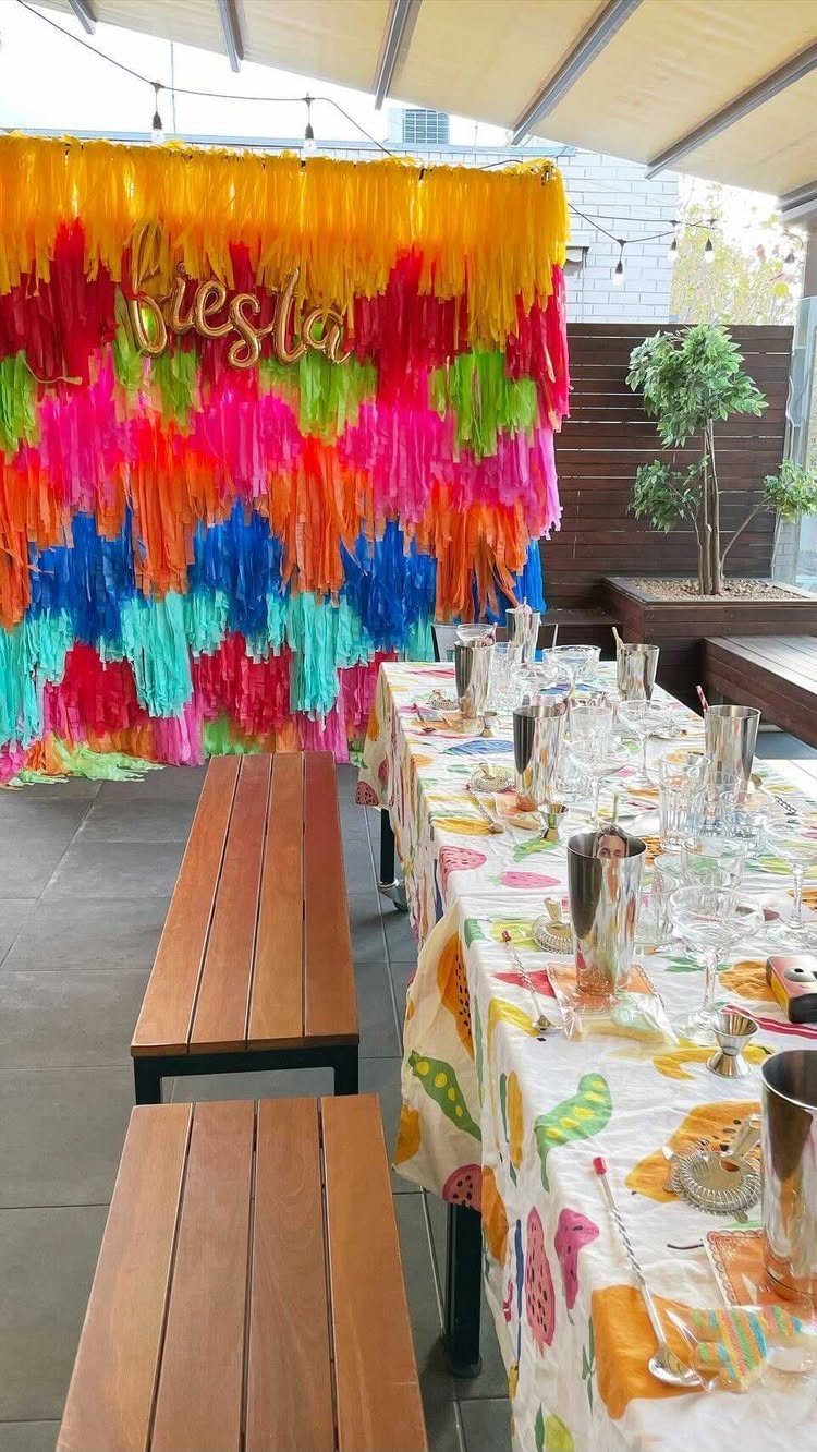 Colorful fiesta party setup with a vibrant fringe backdrop and decorated dining table.