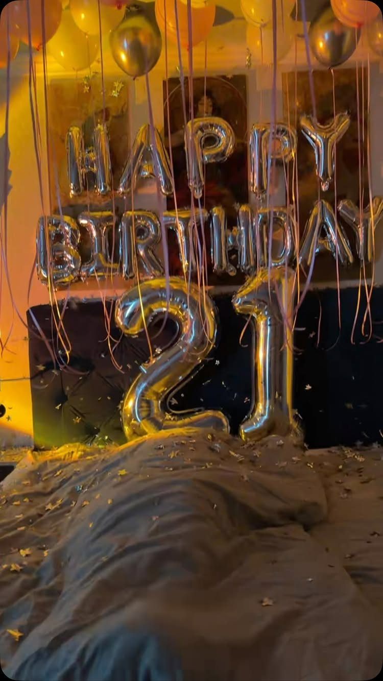 Silver foil balloons spelling Happy Birthday 21 with gold balloons and star confetti.