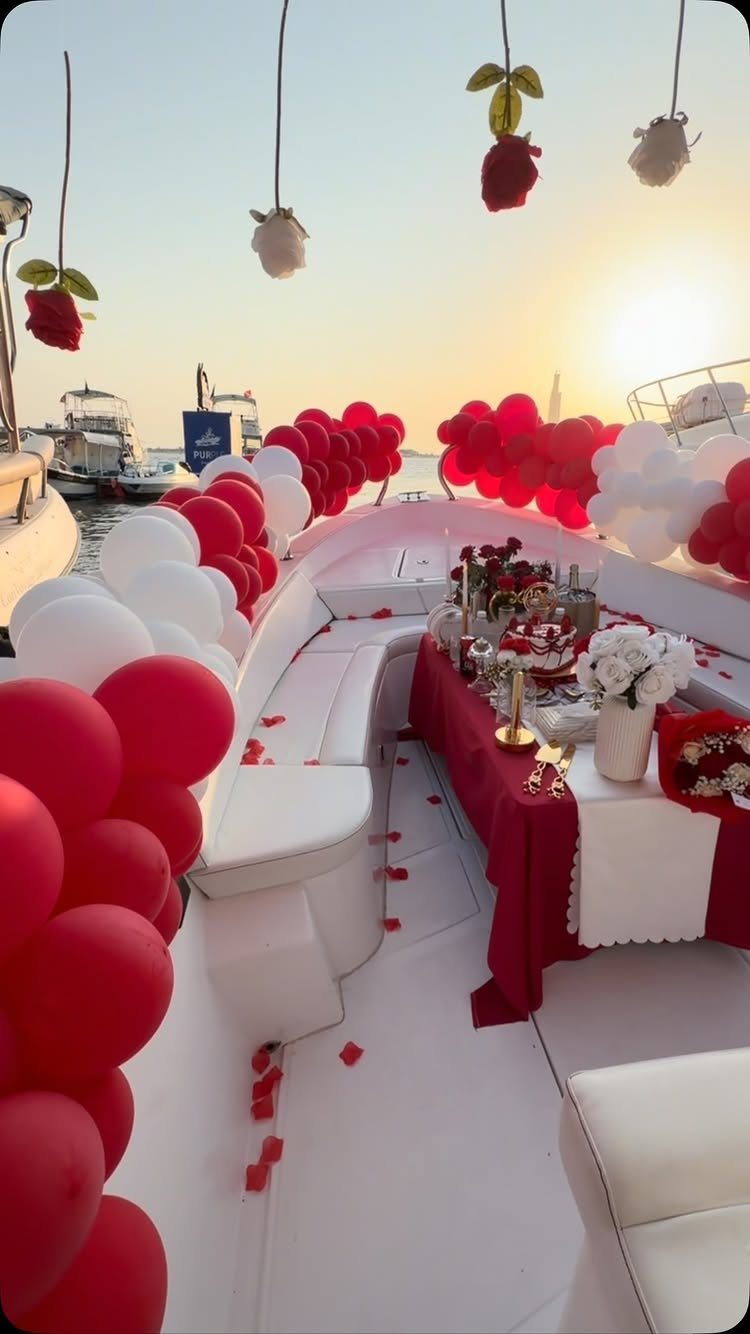 Yacht deck decorated with red and white balloons and roses during a sunset cruise.