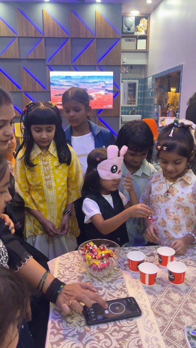 Children playing a blindfolded game with candy at a home birthday party.