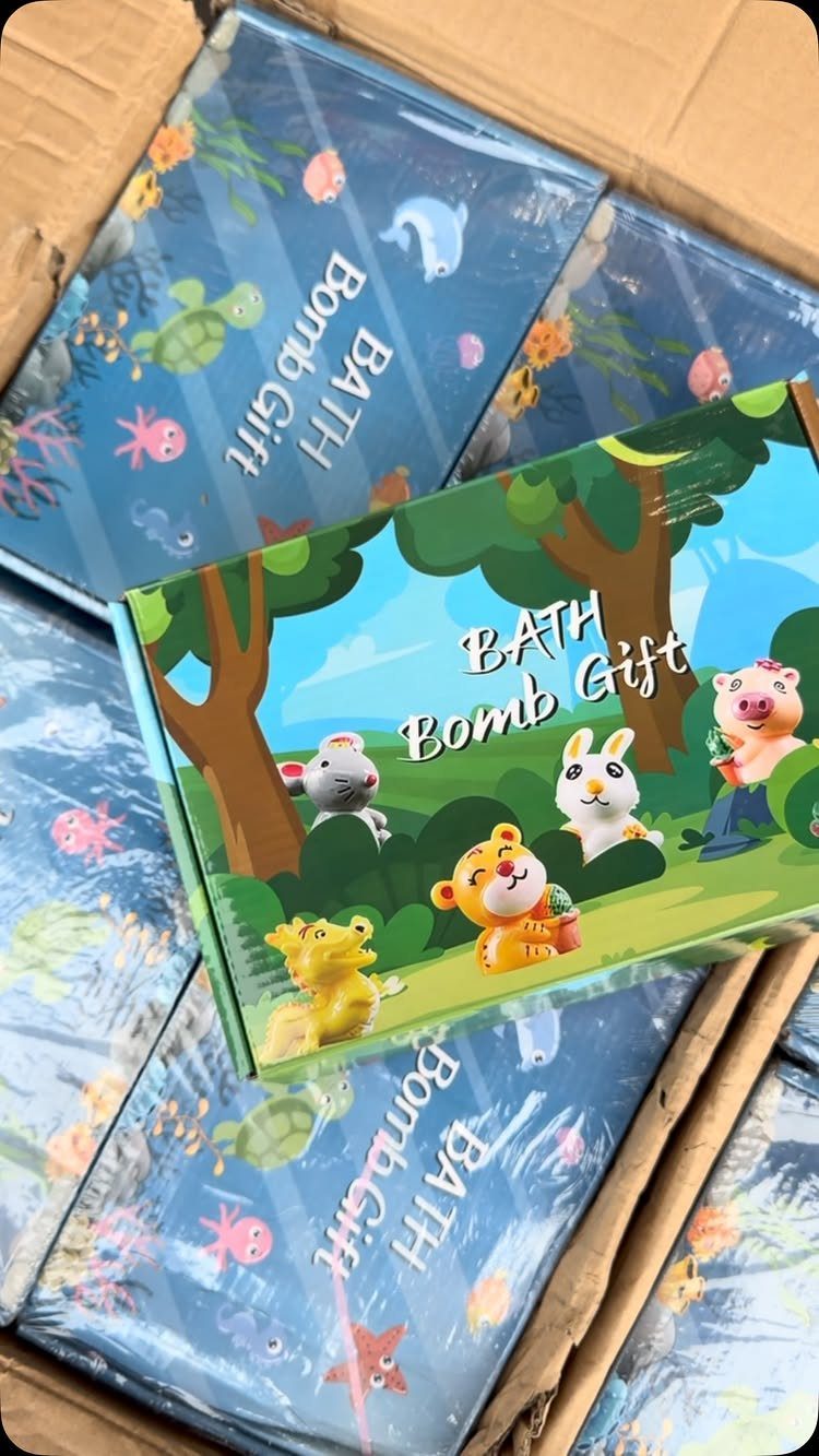 Bath bomb gift boxes with cartoon animals inside a cardboard shipping box.