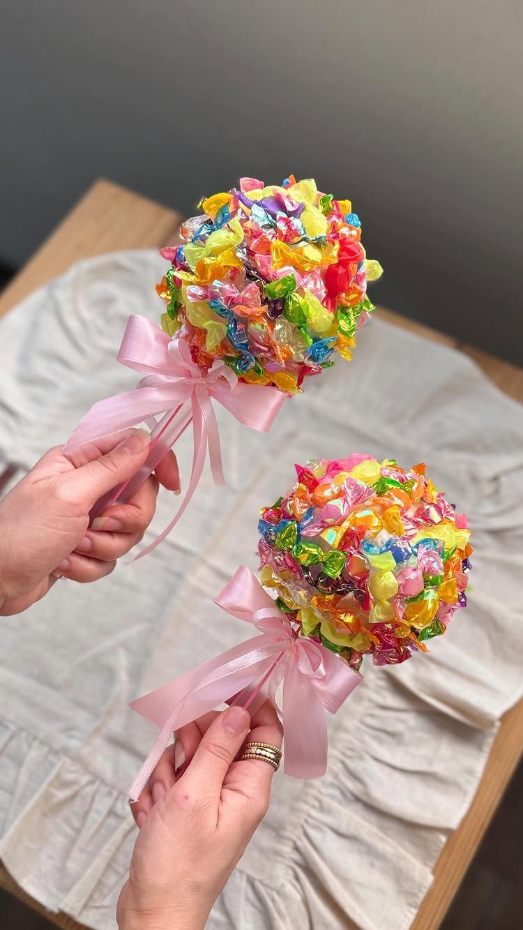 Colorful candy bouquets tied with pink ribbons held by two hands.
