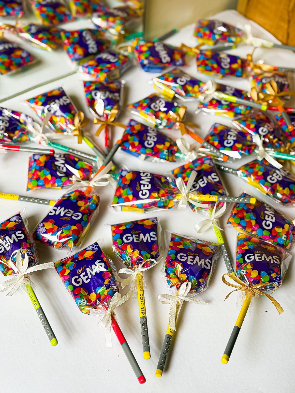 Purple Gems candy packets tied to pencils with ribbons as party favors.
