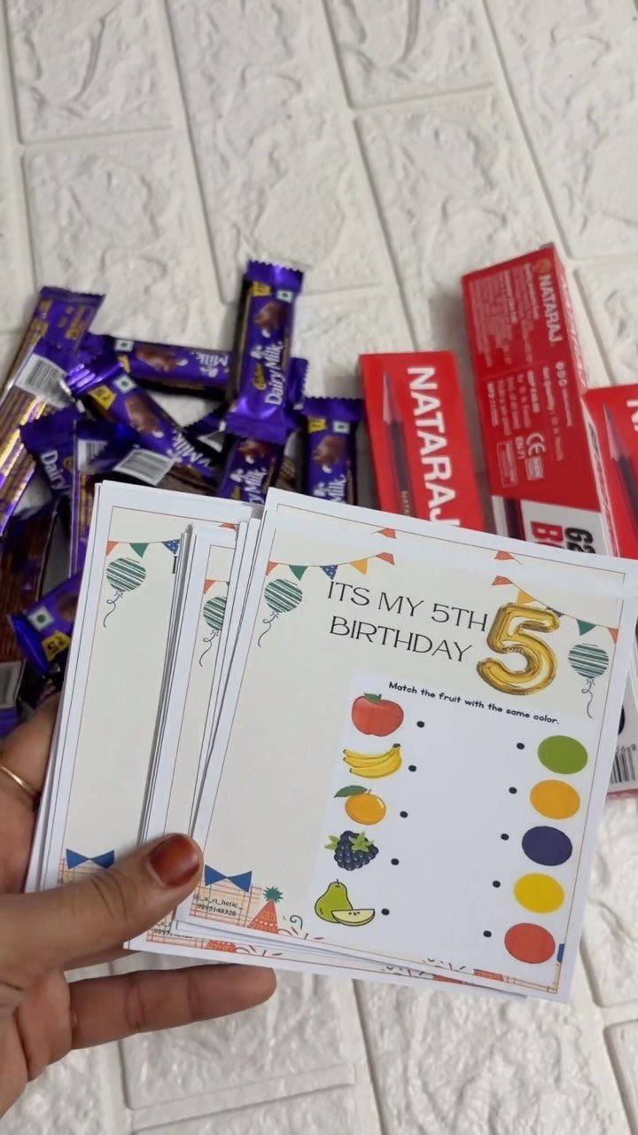 Birthday activity sheets held by a hand with chocolates and pencils in background