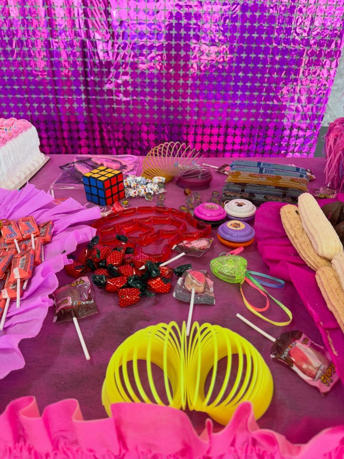 Party favors and candies spread across a purple table with a shimmering backdrop.
