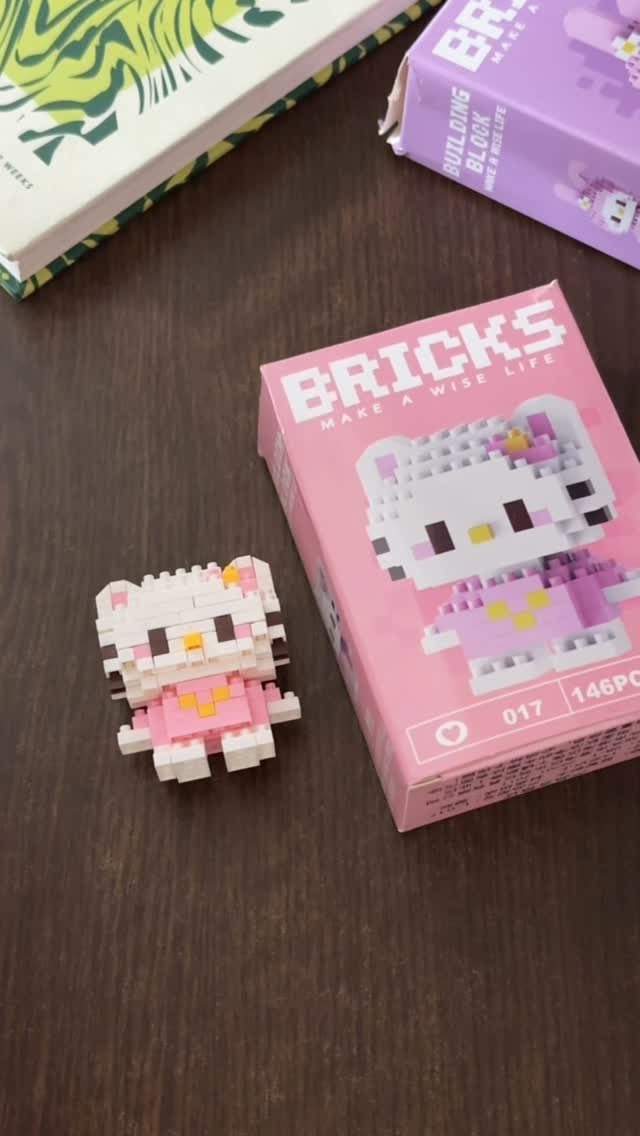Mini building block cat figure and its pink packaging on a wooden table