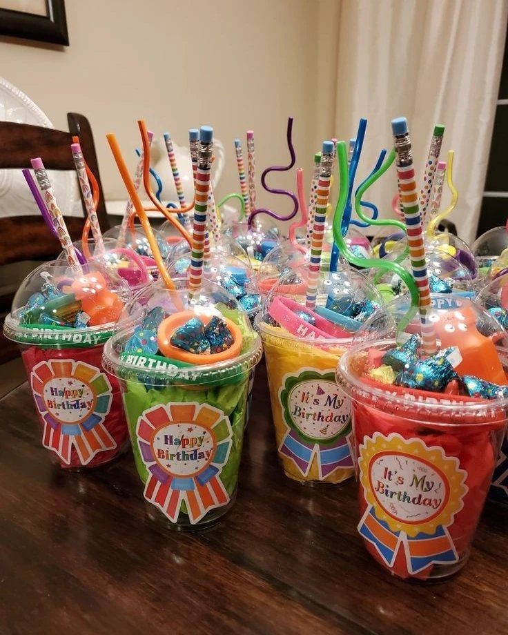 Clear plastic cups filled with colorful candy and straws as birthday party favors.