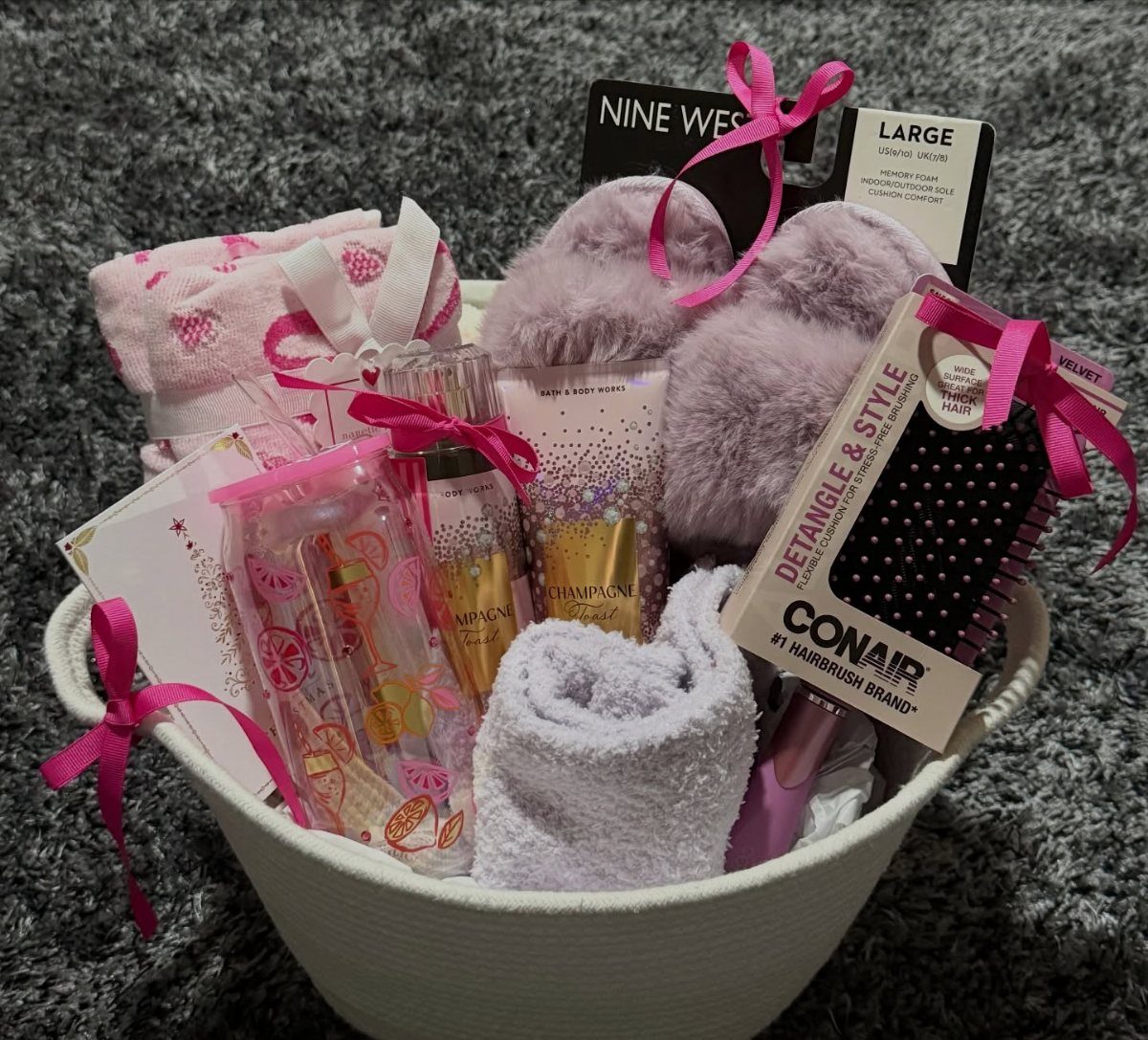 White gift basket filled with purple slippers, pink hairbrush, and spa beauty products.