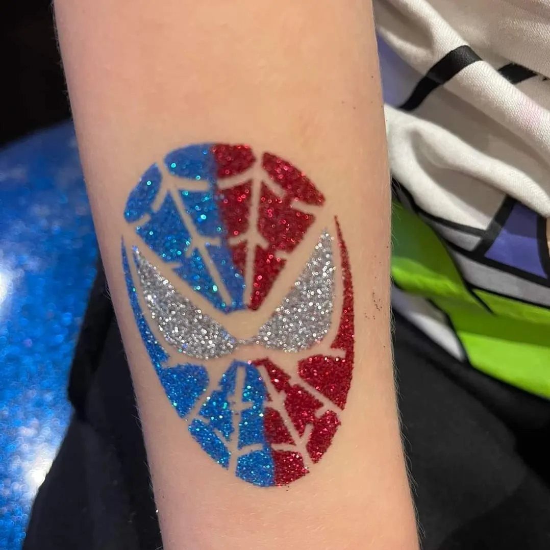 Glittery Spider-Man mask temporary tattoo in red, blue, and silver on a forearm.