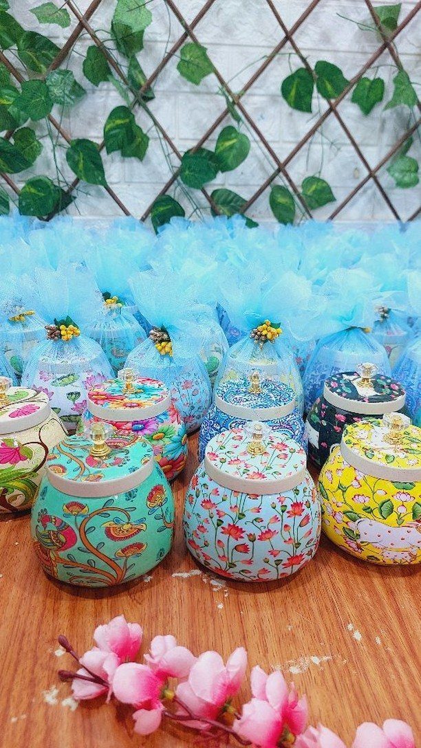 Colorful patterned jars with blue tulle bows arranged on a wooden table.
