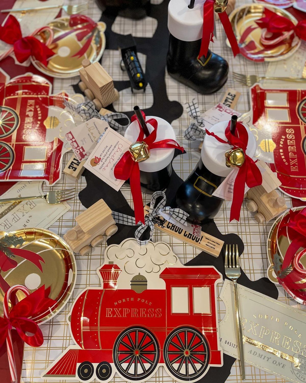 Red and gold table decorations featuring North Pole Express trains and boot-shaped containers.