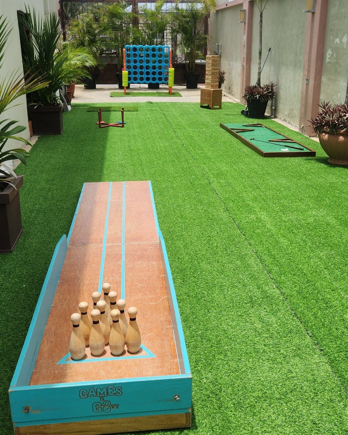 Oversized wooden bowling, Connect Four, and Jenga games on a green turf lawn.