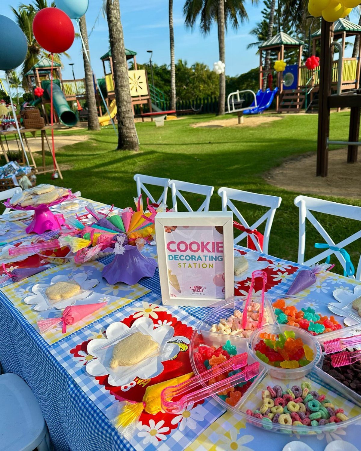 Cookie decorating station with plain cookies and colorful toppings on a park table.