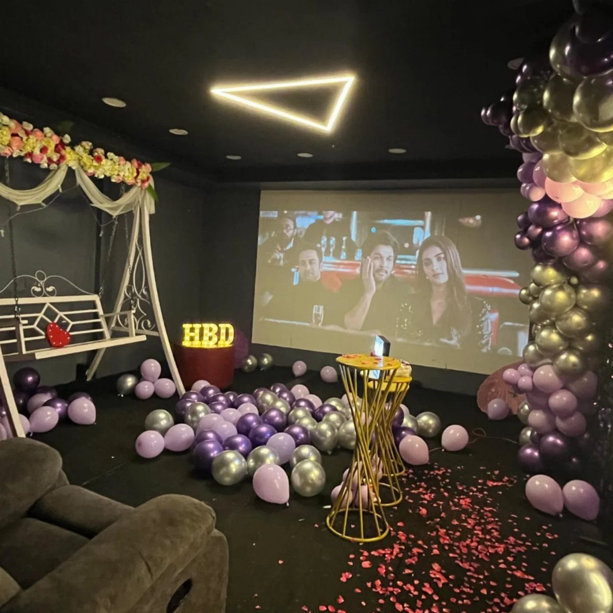Birthday decorated room with purple balloons and a large movie projection screen.