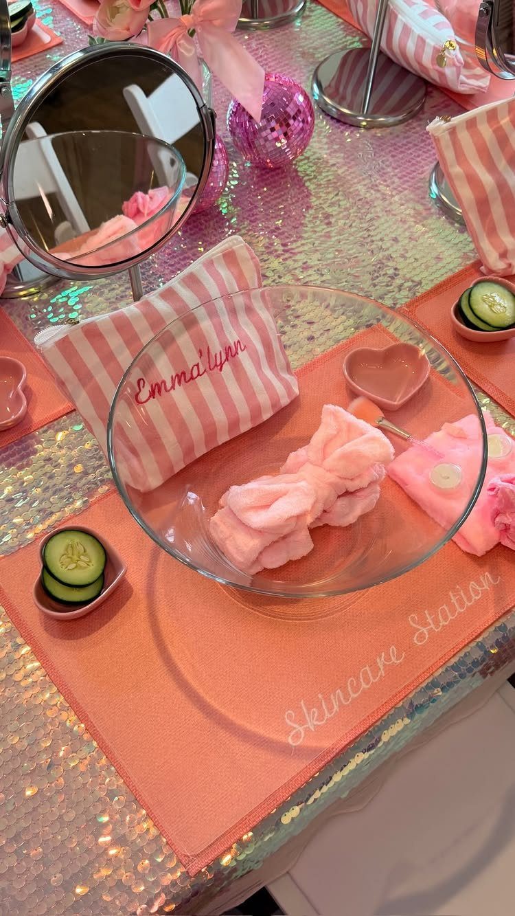 Pink skincare station setup with sponges, cucumber slices, and a mirror on sparkly tablecloth