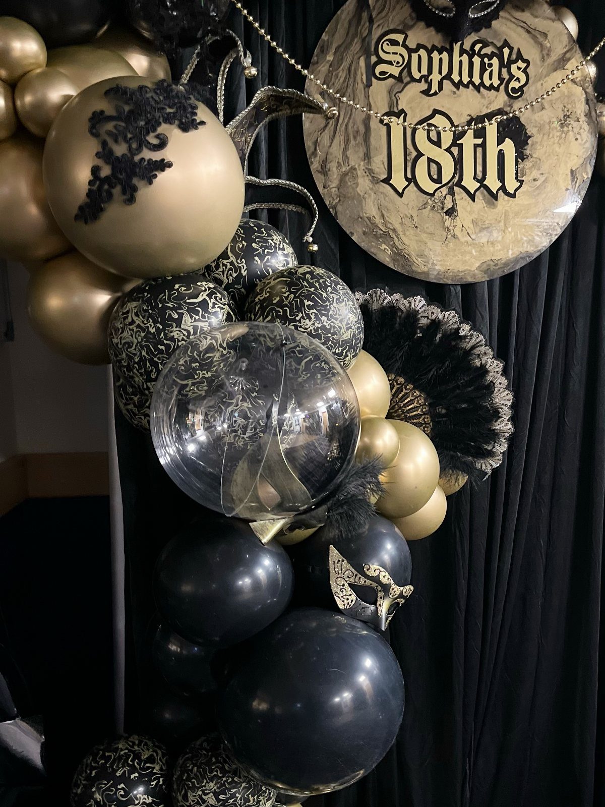 Gold and black balloon arch with a sign reading Sophia's 18th birthday