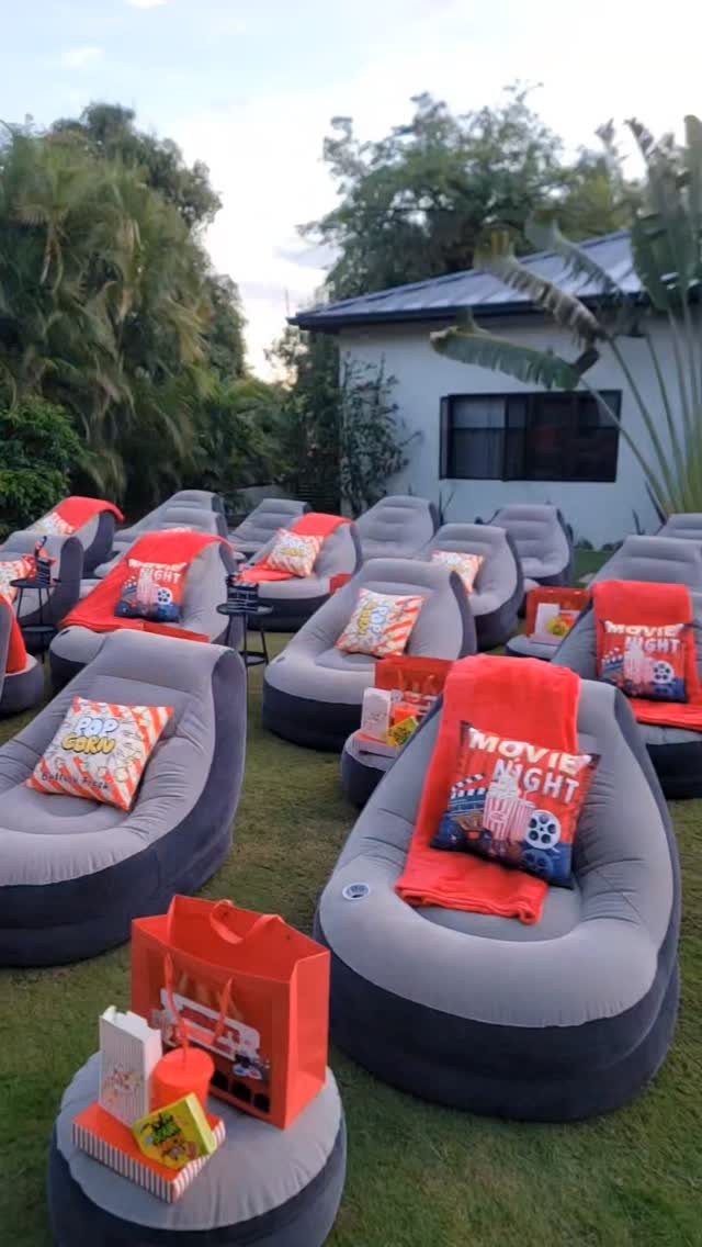 Inflatable grey lounge chairs with movie-themed pillows and red blankets on a lawn