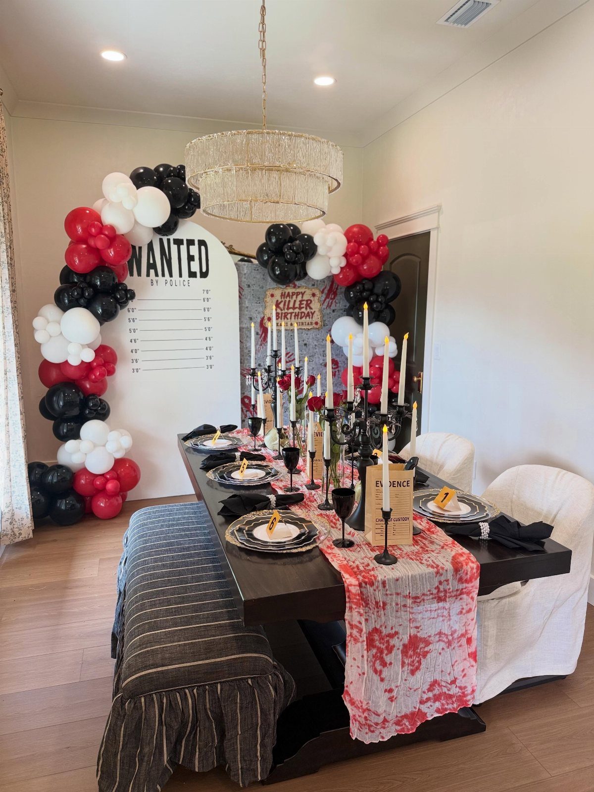 Dining table set for a murder mystery party with red and black decorations.