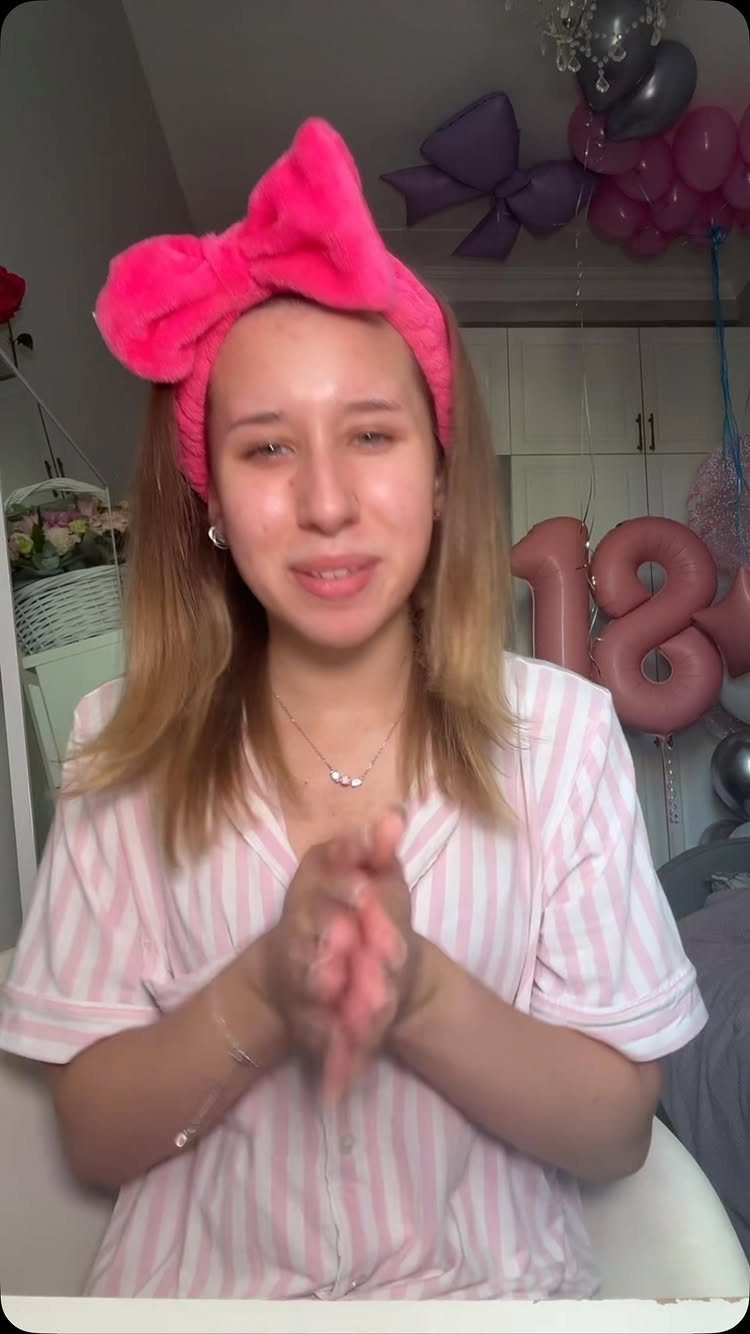 Young woman in pink pajamas with 18th birthday balloons in the background