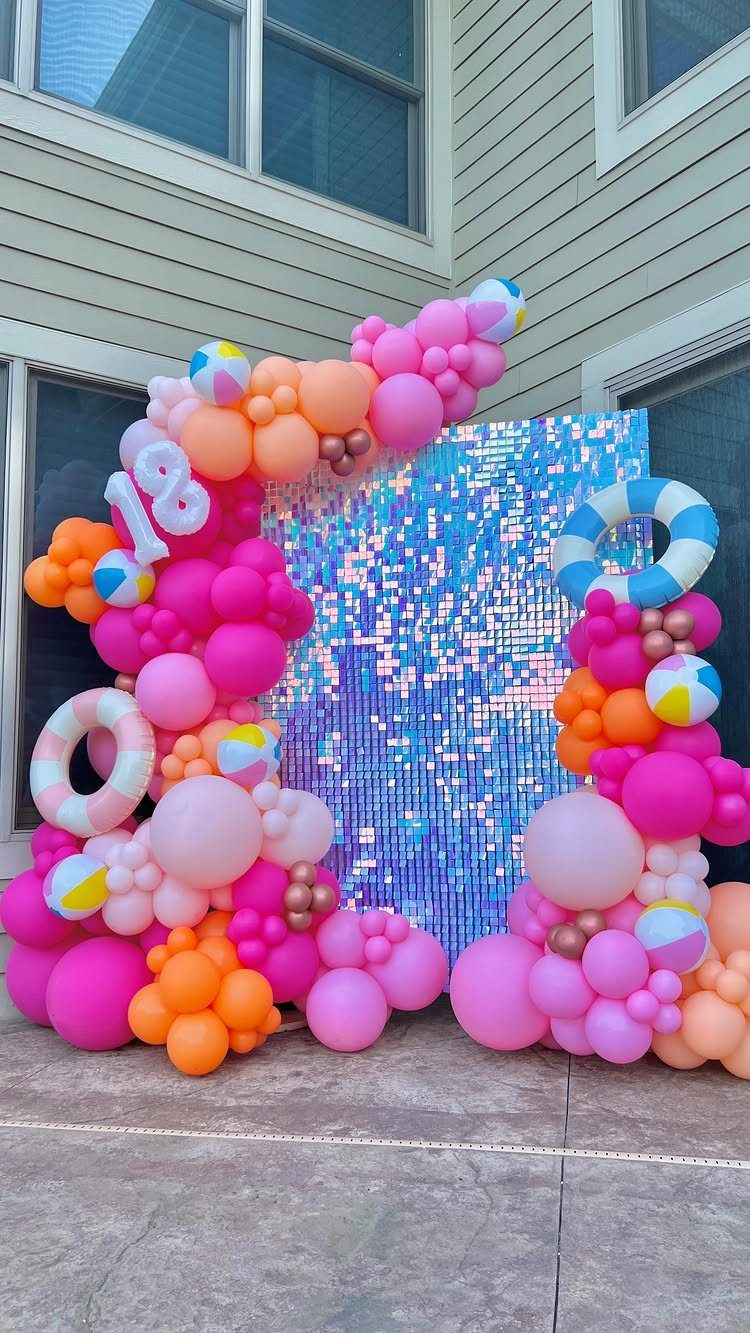 Festive 18th birthday backdrop with pink balloons, beach balls, and a blue sequin wall.