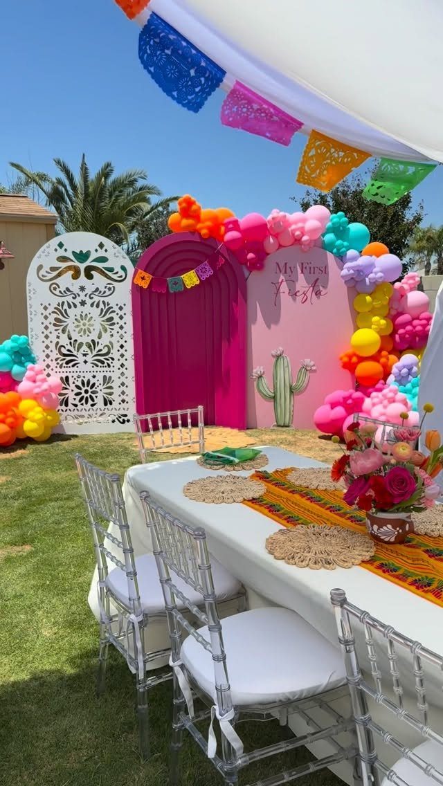 Fiesta party setup with colorful balloons, papel picado banners, and a decorated table.