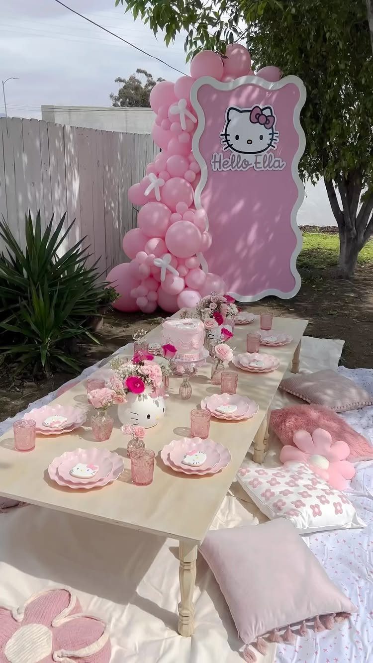 Hello Kitty themed birthday party setup with pink balloons, table, and decorative sign.