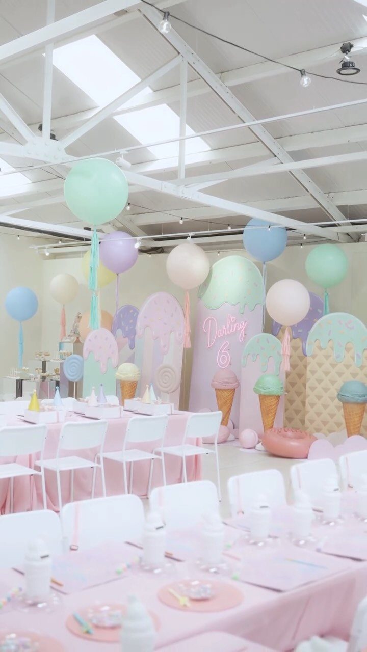 Pastel birthday party setup with ice cream cone cutouts and pink tables.