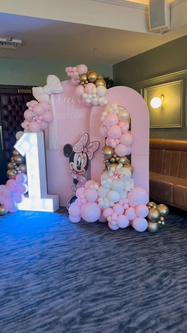 Minnie Mouse birthday setup with pink and gold balloons and a large glowing one.