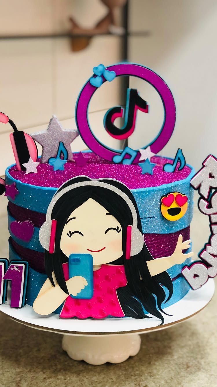 TikTok themed birthday cake with glittery frosting, logo topper, and cartoon girl.