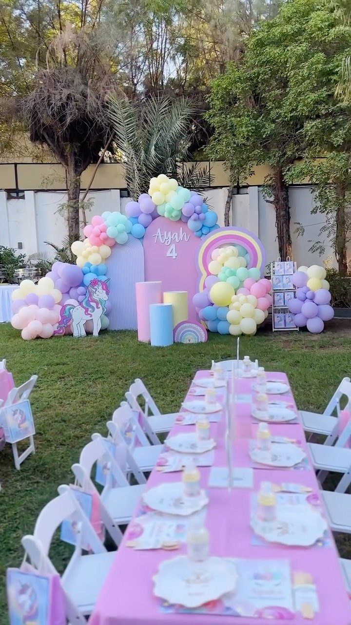 Pastel balloon arch and pink table setting for a unicorn themed birthday party.