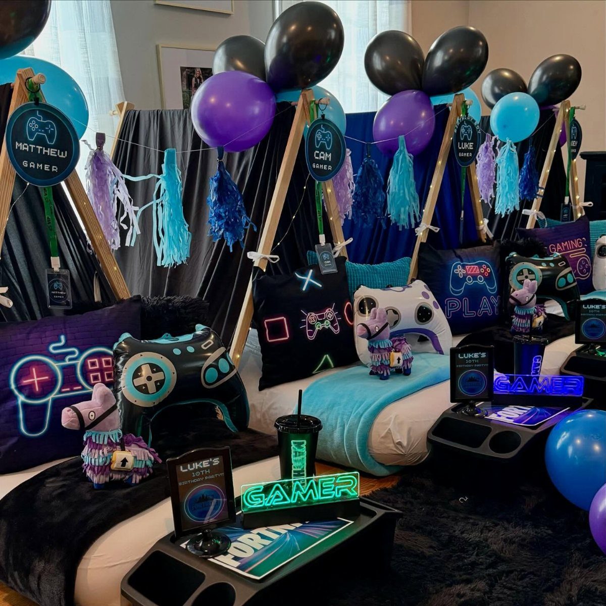 Gaming themed teepee tents with blue and purple balloons and controller pillows.