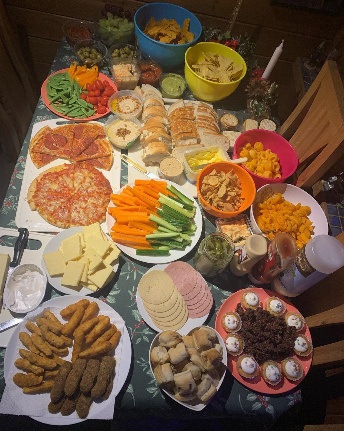 Assorted party snacks including pizza, vegetables, chips, and cupcakes spread across a table.