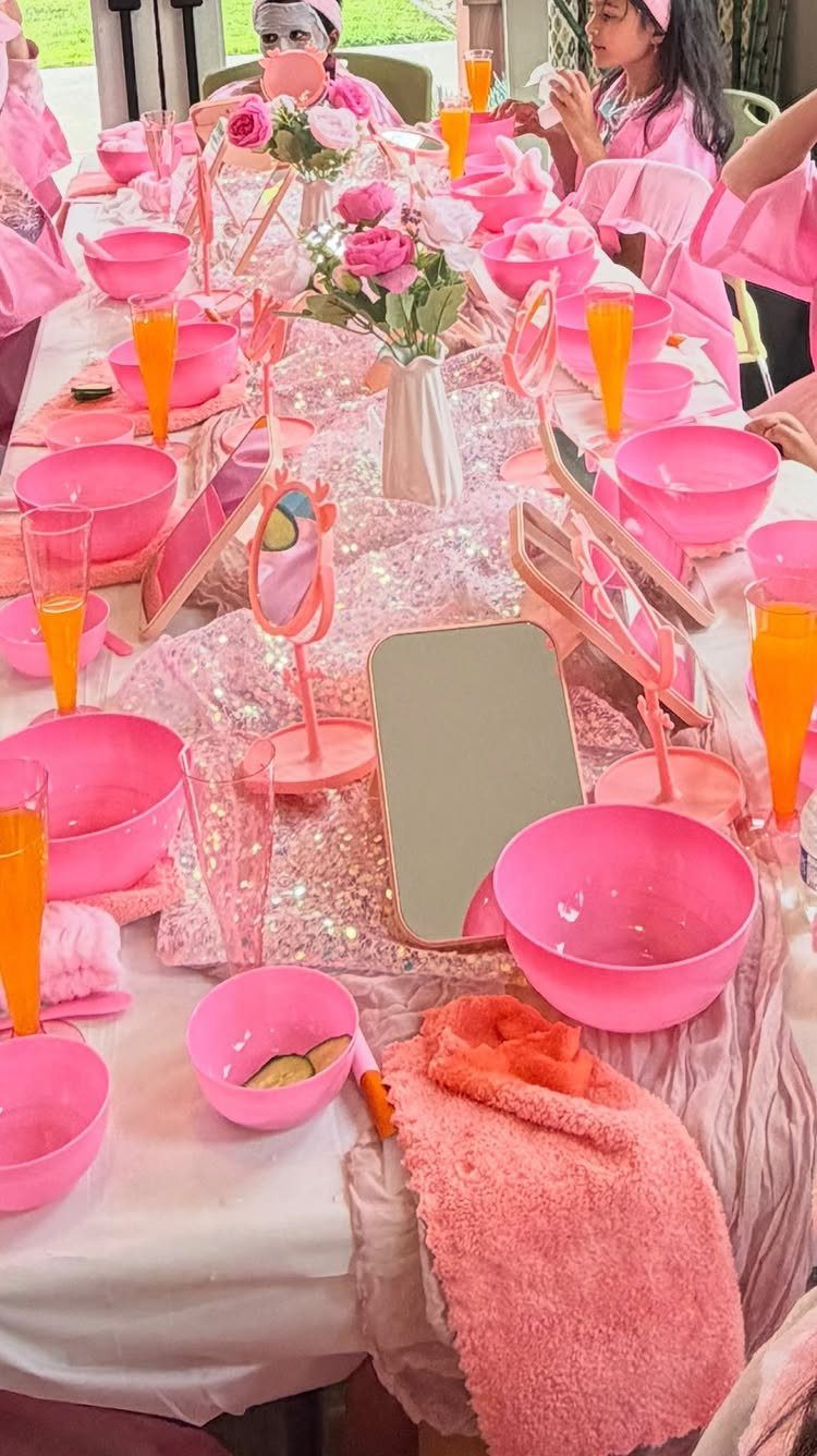 Spa party table setup with pink bowls, mirrors, and roses for guests.