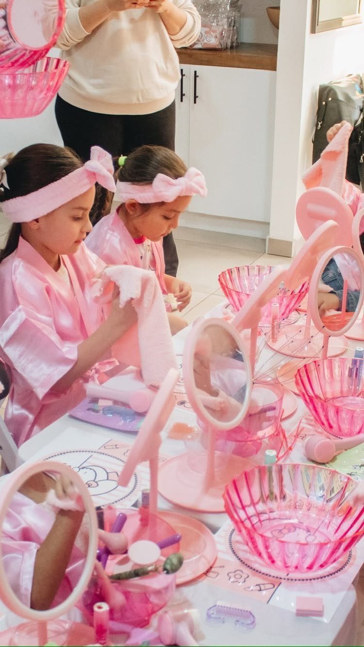 Two girls in pink robes at a spa party table with beauty accessories
