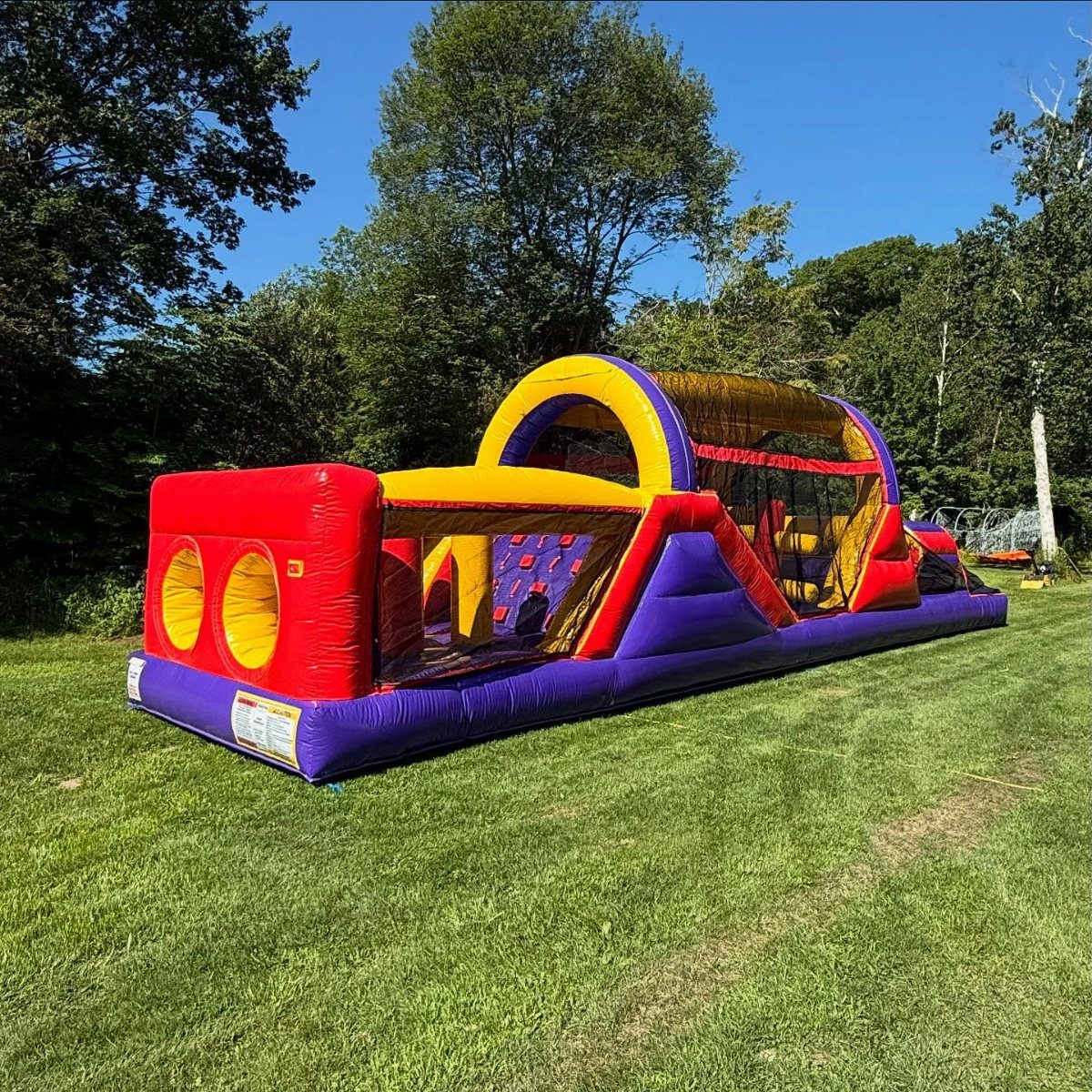 Colorful inflatable obstacle course on a green lawn under a clear blue sky.