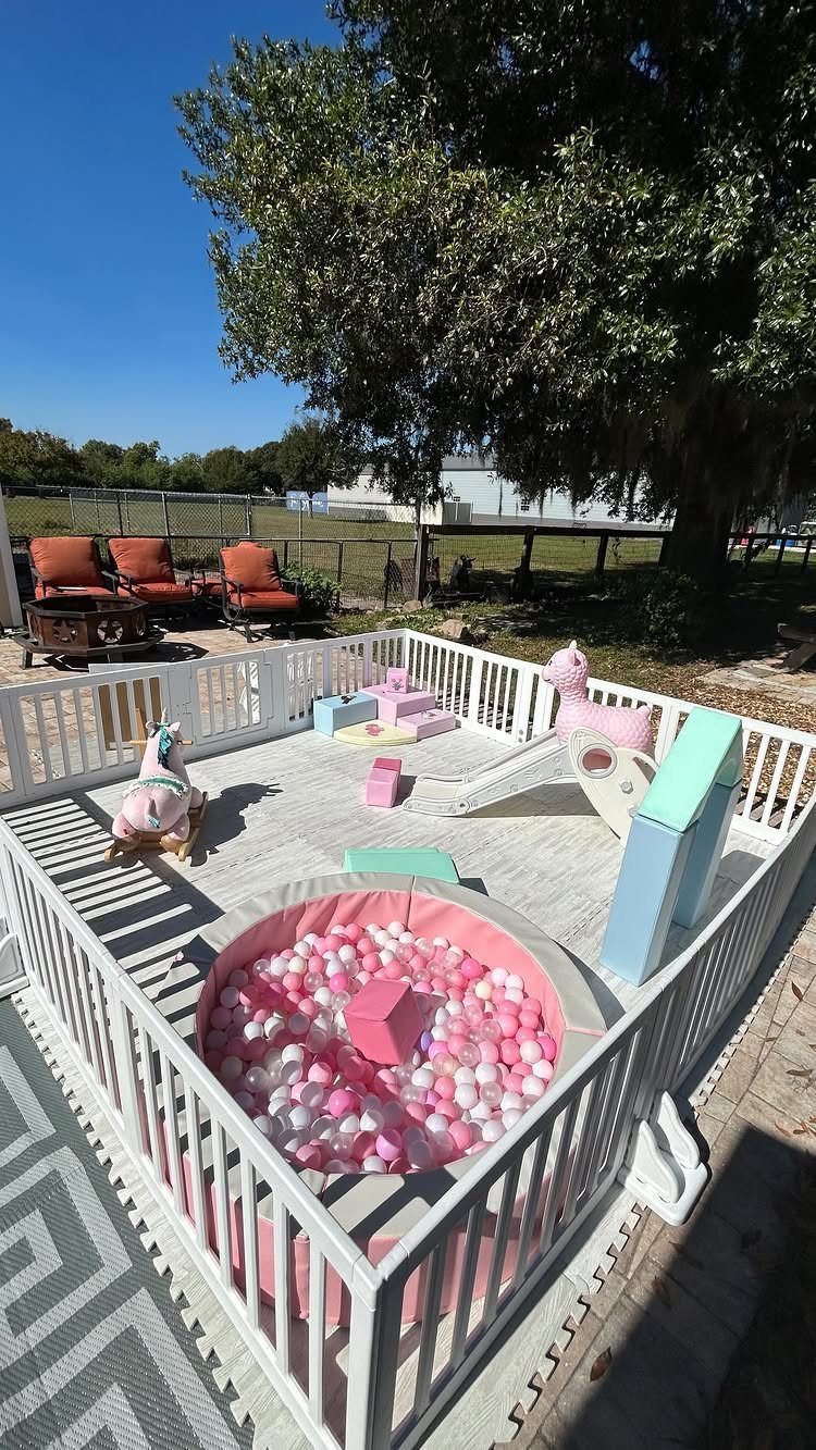 Outdoor soft play area with pink ball pit, slide, and foam blocks.